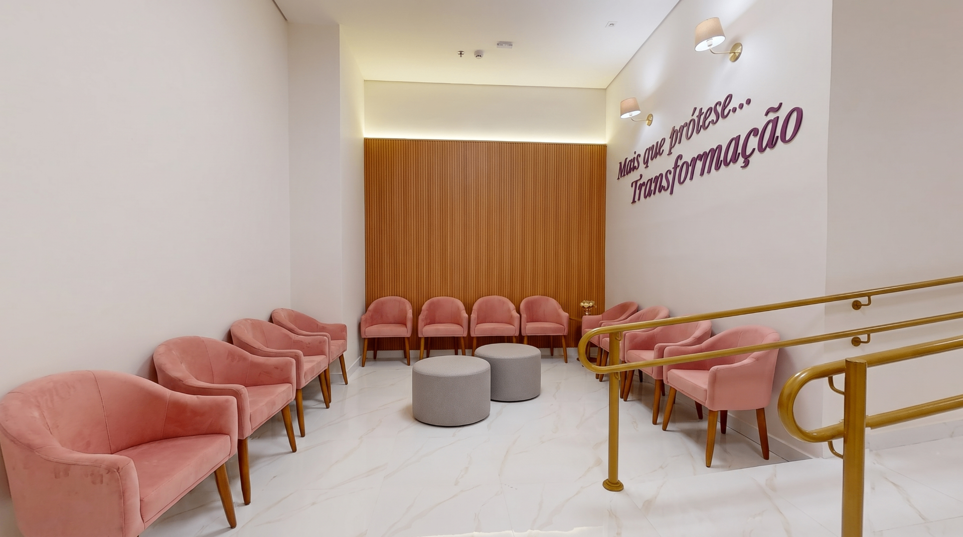 Sala de espera da Clínica Impla com poltronas rosa em veludo e a frase 'Mais que prótese... Transformação' na parede